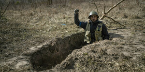 Ein ukrianischer Soldat reckt die Faust aus einem Graben