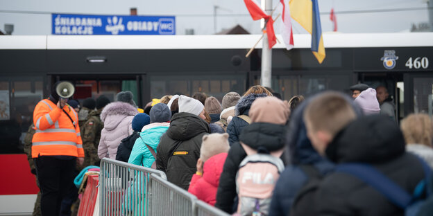 Geflüchtete aus der Ukraine stehen kurz hinter dem Grenzübergang von der Ukraine nach Polen für einen Bus an.