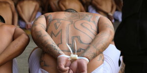 Auf dem nackten Rücken eines Mannes mit gefesselten Händen sind die Buchstaben M und S eintätowiert