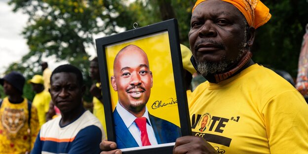 Ein Mann mit gelbem Shirt hält das Porträt des Oppositionspolitikers Nelson Chamisa