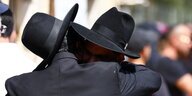 Zwei Männer mit schwarzen Hüten umarmen sich