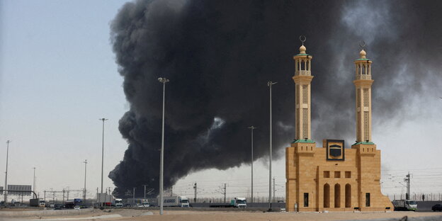 Schwarzer Rauch steigt über einer sandfarbenen Moschee auf.