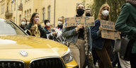 Demonstrierende laufen an einem gelben BMW vorbei. Sie halten Schilder, auf denen steht "FDP - Fick den Planeten" und "Euch gehen die Ausreden aus - uns die Zeit".