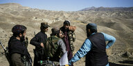 Taliban-Soldaten stehen in einem kargen Tal