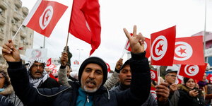Menschen mit den Nationalflaggen Tunesiens demonstrieren auf der Straße