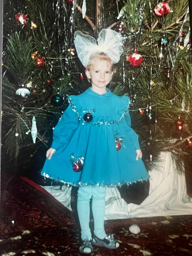 Anna Salita steht mit großer Schleife im Haar vor dem Weihnachtsbaum