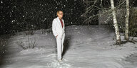 Mann in weißem Anzug in verschneitem Wald bei Nacht