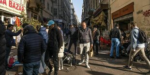 Menschen spazieren eine Strasse mit verschiedenen Läden entlang