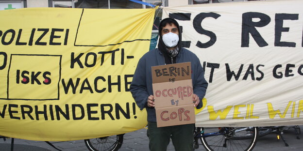 Kundgebungsteilnehmer mit Protestschild auf dem geschrieben steht „Berlin is occupied by Police“