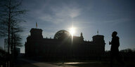 m Gegenlicht der Sonne ist der Reichstag nur als Silhouette zu sehen.