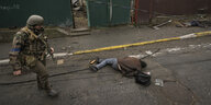Ein ukrainischer Soldat geht an einem leblosen Körper vorbei, der auf einer Straße im ehemals russisch besetzten Kiewer Vorort Butscha liegt.