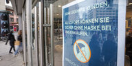 Schild "Ab sofort können sie sicher ohne Maske bei uns einkaufen" steht am Eingang zu einem Kaufhaus in der Frankfurter Innenstadt