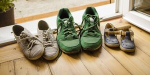 Drei Paar Schuhe: Frauenturnschuhe, Männerturnschuhe und Kinderschuhe