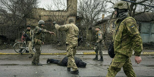 Ukrainische Soldaten steht vor einer Leiche