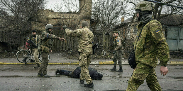 Ukrainische Soldaten steht vor einer Leiche