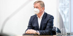 Matthias Brückmann, ehemaliger Vostandsvorsitzender der EWE AG, sitzt im Anzug und mit Mund-Nasen-Schutz im Gerichtssaal