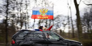 Zwei Frauen halten eine russische Fahne aus einem fahrenden Auto