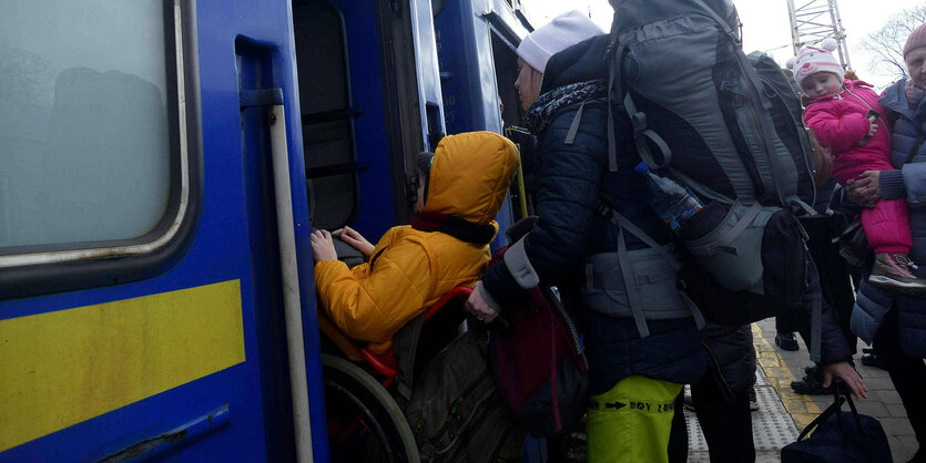 Eine Person in Rollstuhl wird in einen Eisenbahnwagon geladen