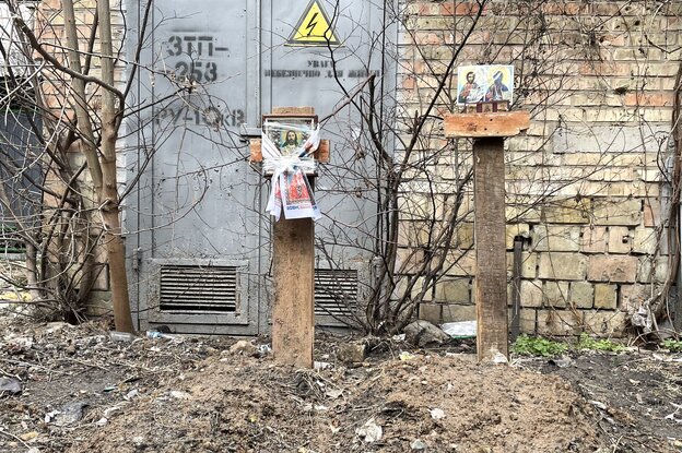 Zwei Kreuz, die mit Heiligenbildern versehen sind und die darunter liegenden Gräber Zwei Kreuz, die mit Heiligenbildern versehen sind und die darunter liegenden Gräber
