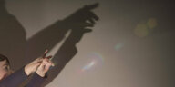 Ein Kind wirft mit seine Händen Schatten an die Wand