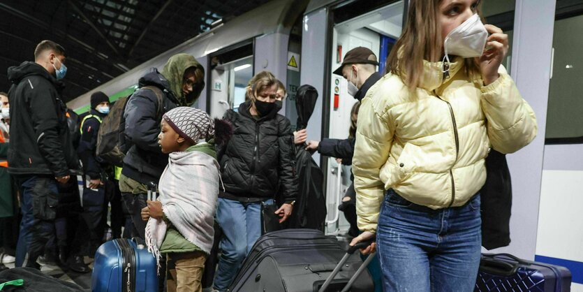 Menschen mit Koffern stehen vor einem Zug