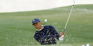 Tiger Woods beim Golfschlag. Sand spritzt auf