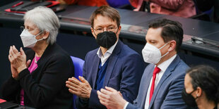 Karl Lauterbach sitzt mit weiteren Abgeordneten im Bundestag und applaudiert