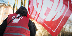 Frau mit GEW Berlin Weste, die eine rote GEW Fahne schwenkt