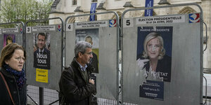 Zwei Menschen gehen an Wahlplakaten von Politiker*innen vorbei