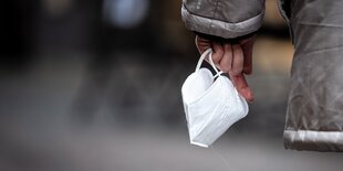 Ein Mensch hält eine Maske in der Hand