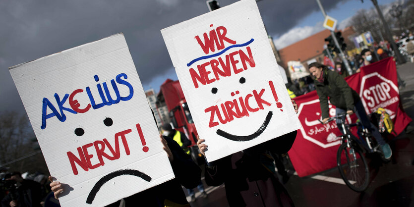 Zwei Demonstrant*innen halten Schilder hoch auf denen steht: "Akelius nervt - wir nerven zurück!"