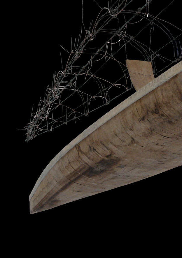 Ein Boot aus zwei Hälften: die eine ist aus Holz, die andere aus Stacheldraht