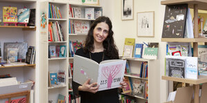 Mariela Nagle hält ein Buch in den Händen, sie betreibt in Berlin eine Buchhandlung im Bezirk Prenzlauer Berg