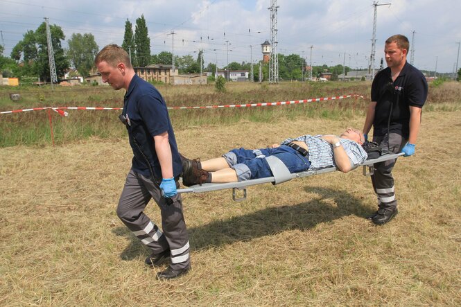 Zwei Sanitäter transportieren einen Mann auf einer Krankenliege im Rahmen einer Großübung der Medical Task Forces