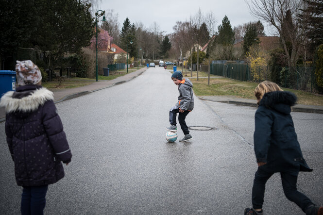 Ein paar Kinder spielen in dem Dorf Panketal Fußball auf einer nicht befahrenen Straße