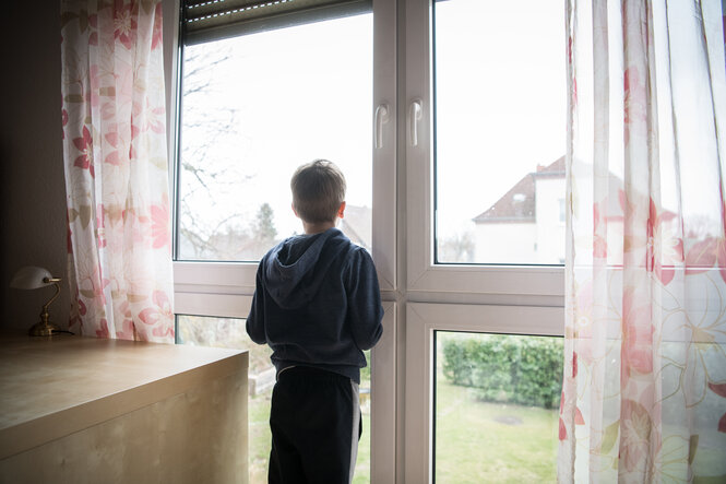 Sohn von Eugenia K. steht am Fenster des Zimmers im Haus der Gastfamilie