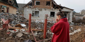 Eine Frau steht vor Trümmern in Chernihiv