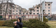 Eine Frau macht ein Selfie vor einem zerstörten Gebäude