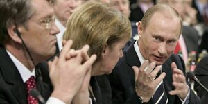 Drei Leute diskutieren: Viktor Juschenko, Angela Merkel, Wladimir Putin