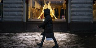 Ein Mensch in Kapuzenjacke läuft an einem Schaufenster vorbei