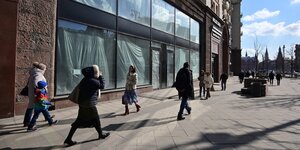Menschen laufen auf der Straße an einem geschlossenen Geschäftz vorbei