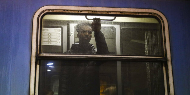 Ein Mann steht am Fenster eines erleuchteten Zuges