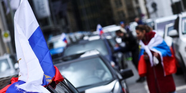 menschen stehen neben Autos, überall sind russische Fahnen
