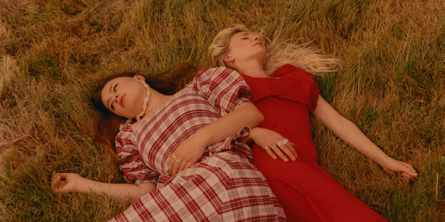 Zwei junge Frauen liegen im Grass