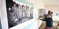 Petar Miloradović und Kurator Željko Dragić bringen Schwarz-Weiß-Fotos an einer Wand an.