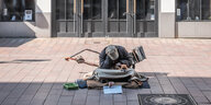 Ein obdachloser Mensch mit Hund auf dem Schoß sitzt vor einem Laden