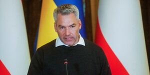 Österreichs Kanzler Karl Nehammer steht vor den Fahnen der Ukraine und Österreichs