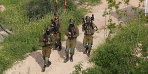 4 schwer bewaffnete israelische Soldaten gehen auf einem Weg