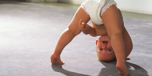 Ein Baby macht einen Kopfstand auf dem Fußboden