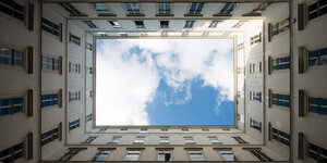 Blauer Himmerl und Wolken durch einen Wohnblock gesehen